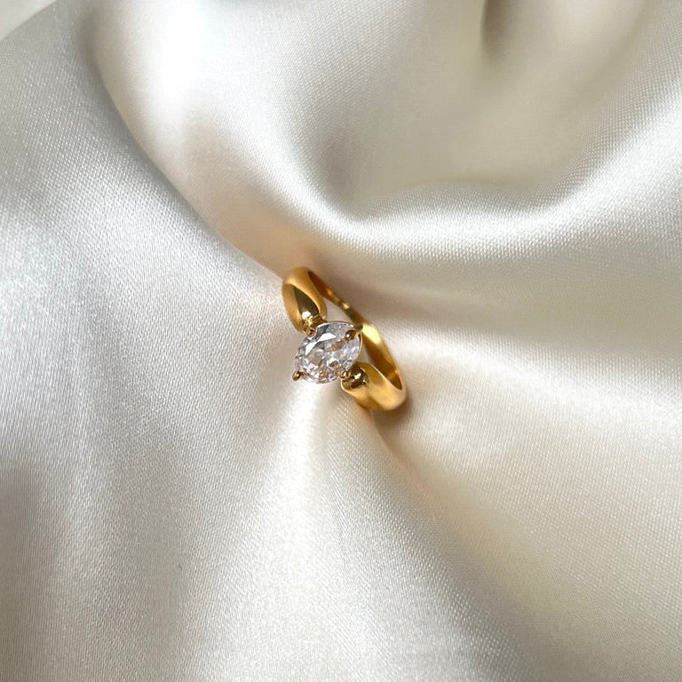 Adele Antique Ring i rostfritt stål med PVD-plätering i 18K guld. Ringen har en slät yta och en oval solitärsten infattad med fyra klor – en klassisk och tidlös design.