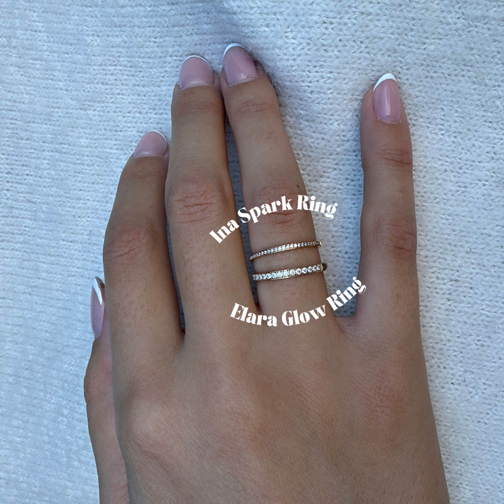 Elara Glow Ring Ina spark ring i guld med klara stenar som löper halvvägs runt ringen. Elegant, tunn och vattentålig ring från Alora Avenue i rostfritt stål med PVD-plätering.