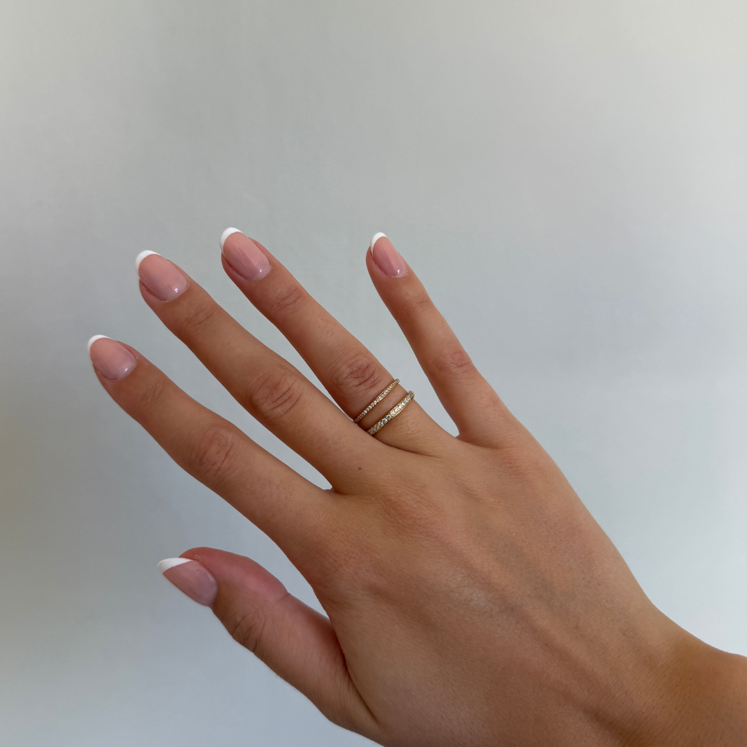 Elara Glow Ring Ina Spark Ring i guld med klara stenar som löper halvvägs runt ringen. Elegant, tunn och vattentålig ring från Alora Avenue i rostfritt stål med PVD-plätering.