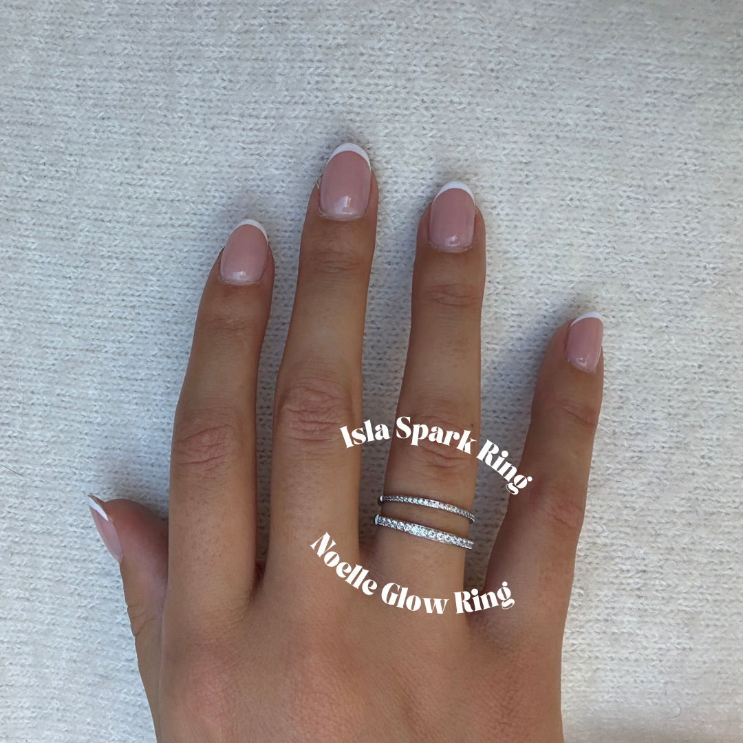 Noelle Glow Ring i silver med klara stenar som löper halvvägs runt ringen. Elegant och vattentålig ring från Alora Avenue i rostfritt stål med PVD-plätering.