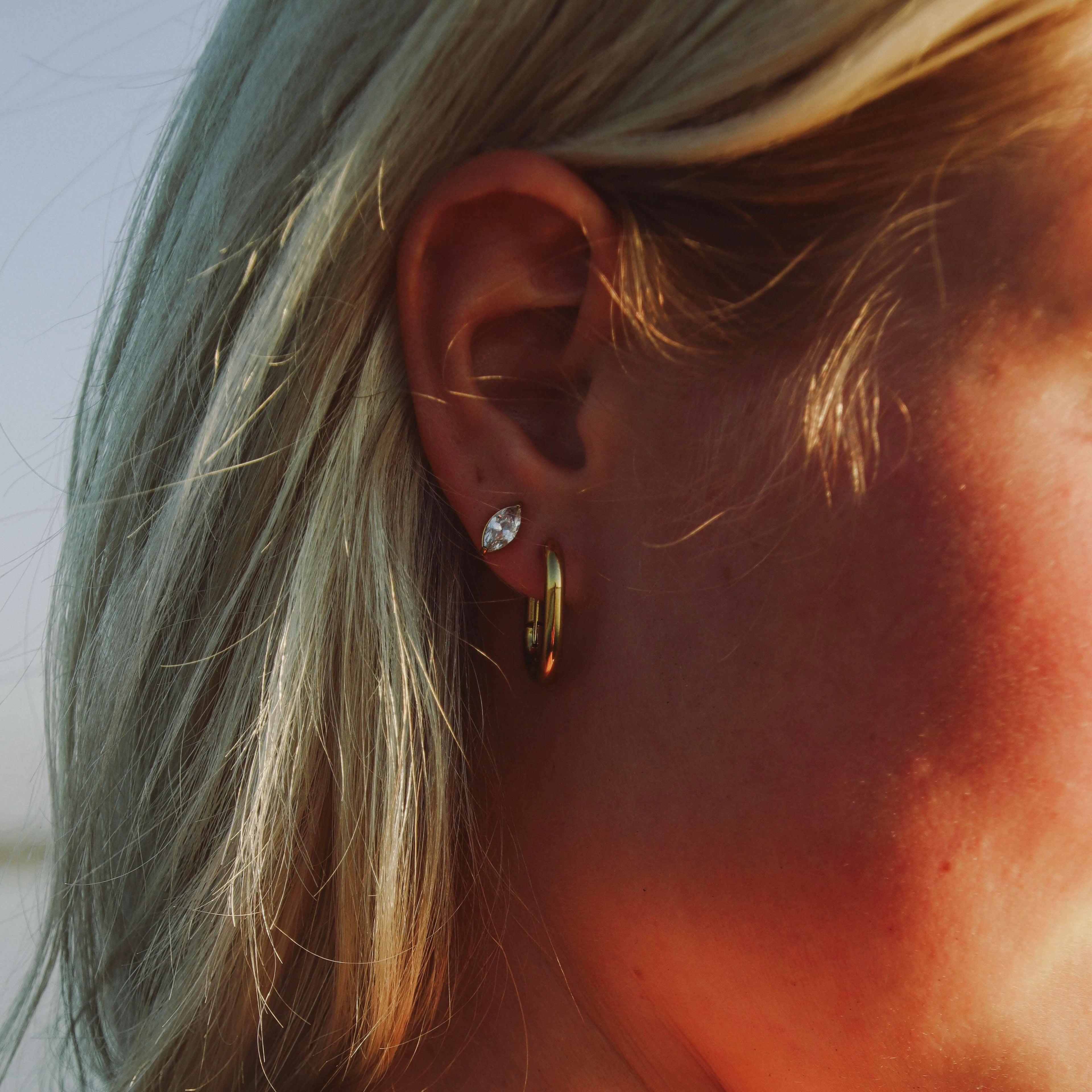 Nara Navette Earrings från Alora Avenue på modell, små eleganta örhängen med gnistrande navettslipad sten i rostfritt stål. Vattentåliga och allergivänliga örhängen som ger en tidlös och lyxig känsla till varje look.