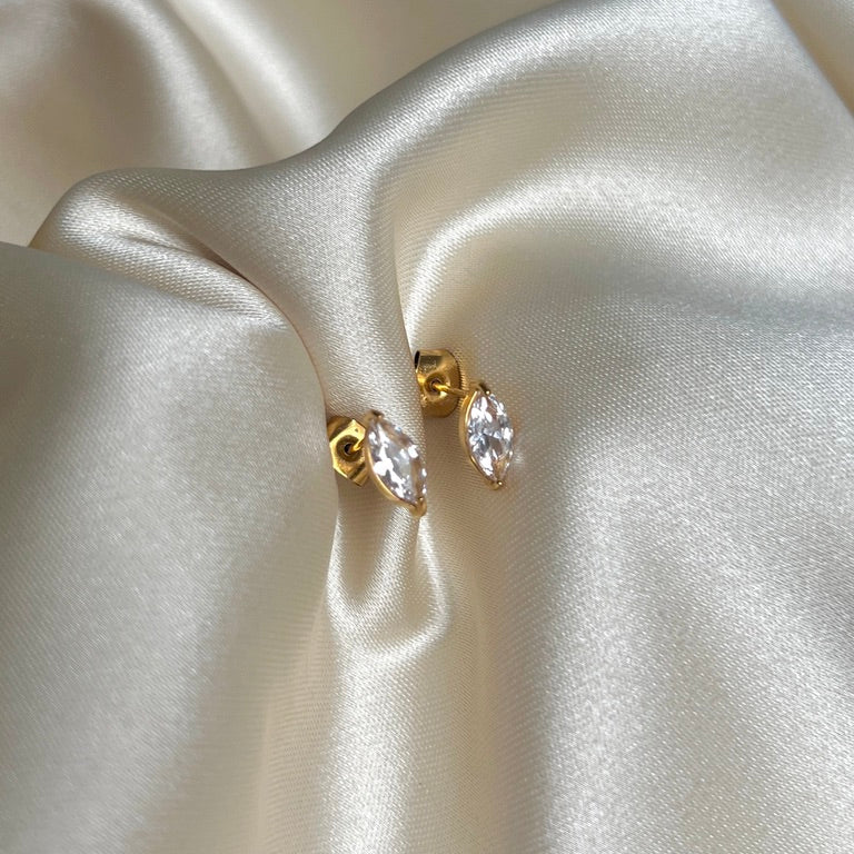 Nara Navette Earrings från Alora Avenue, guldfärgade örhängen i rostfritt stål med navettslipad gnistrande sten. Vattentåliga och allergivänliga örhängen som kombinerar elegans och tidlös design.