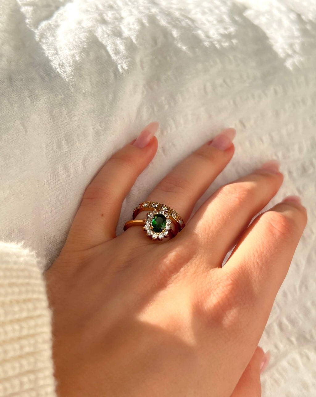Celine Carmose Ring – lyxig guldring med en djupgrön sten i centrum, omgiven av gnistrande vita stenar. Ett tidlöst statement från Alora Avenue med elegant vintagekänsla.