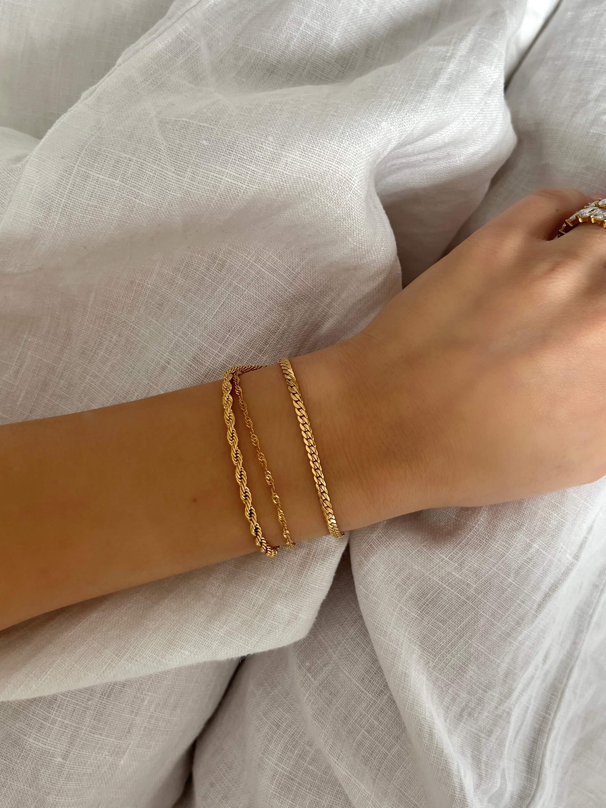 Girly Grace Bracelet – stilrent guldarmband i platt kedjedesign, bärs på handled i linne för en elegant och tidlös look från Alora Avenue